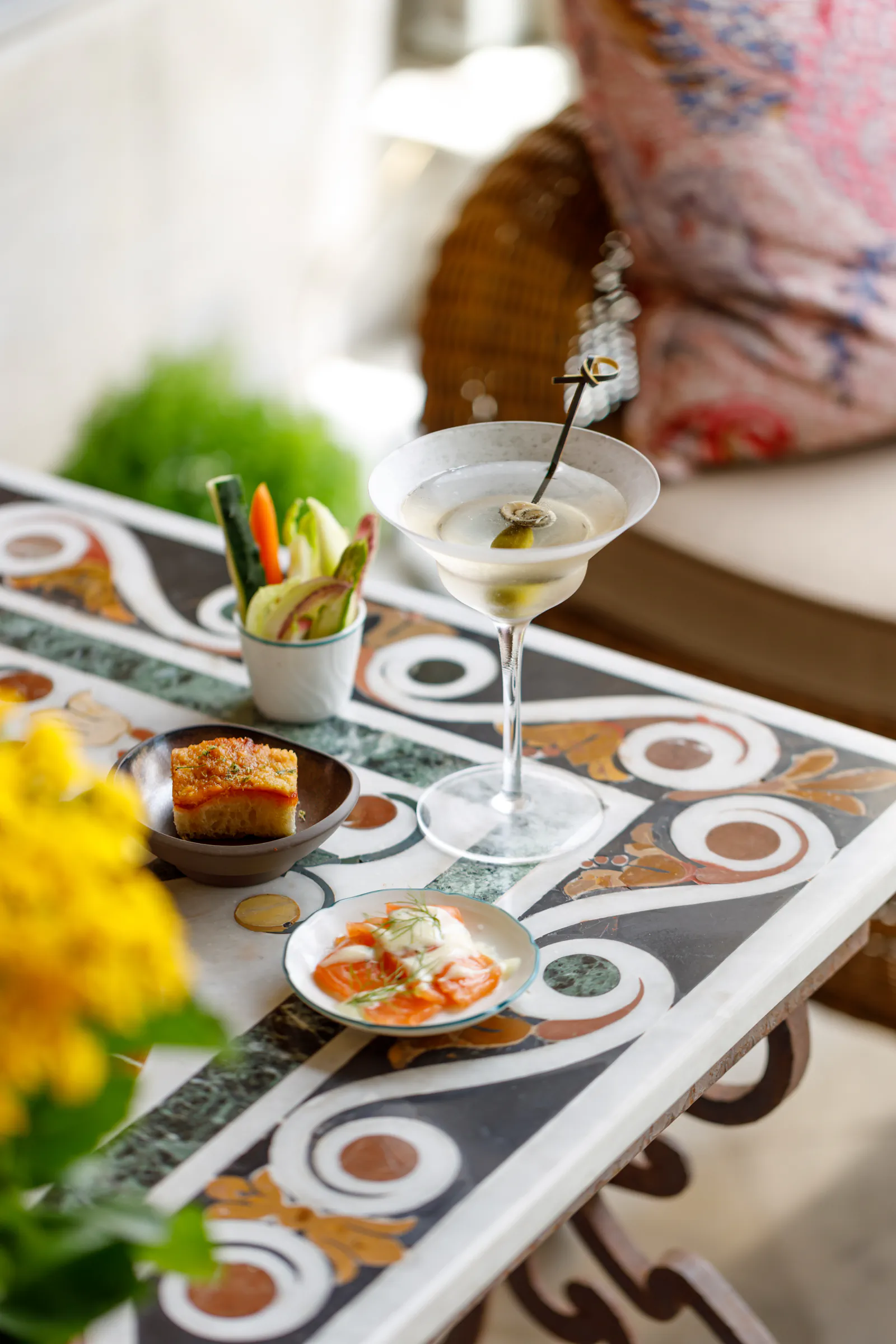 Martini with a vegetable garnish on a decorative tiled table with small snacks at Villa Igiea a Roccoforte Hotel in Palermo, Italy