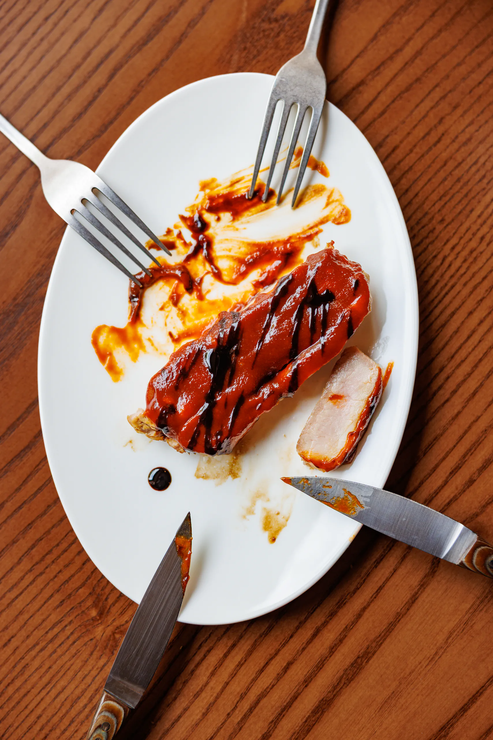 Glazed pork with sauce on a white plate with cutlery - Santopalato, Rome, Italy