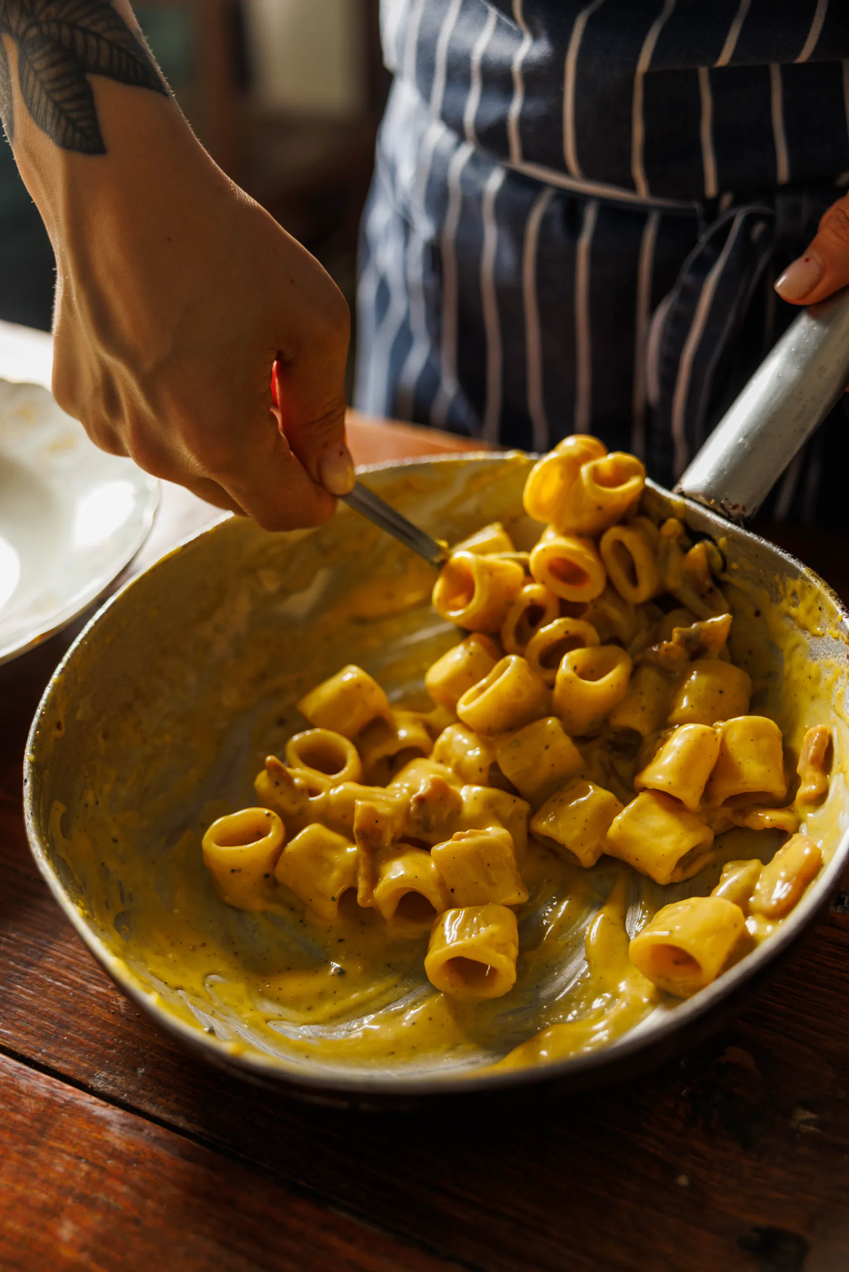 Chef finishing a bowl of carbonara-style pasta - Santopalato, Rome, Italy