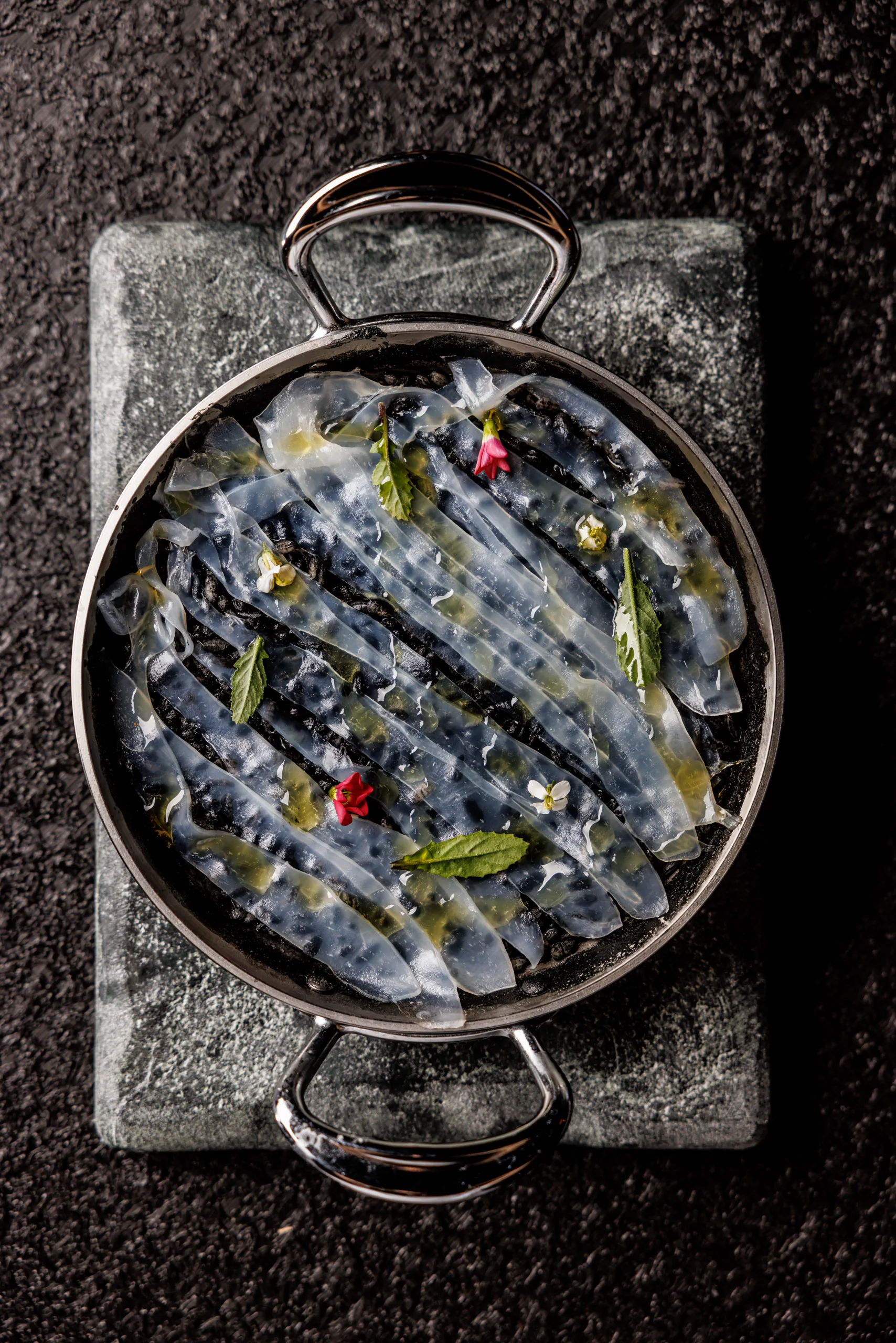 Squid-ink black paella in a pan, seen from above - Chef Giuseppe Iannotti, Naples, Italy