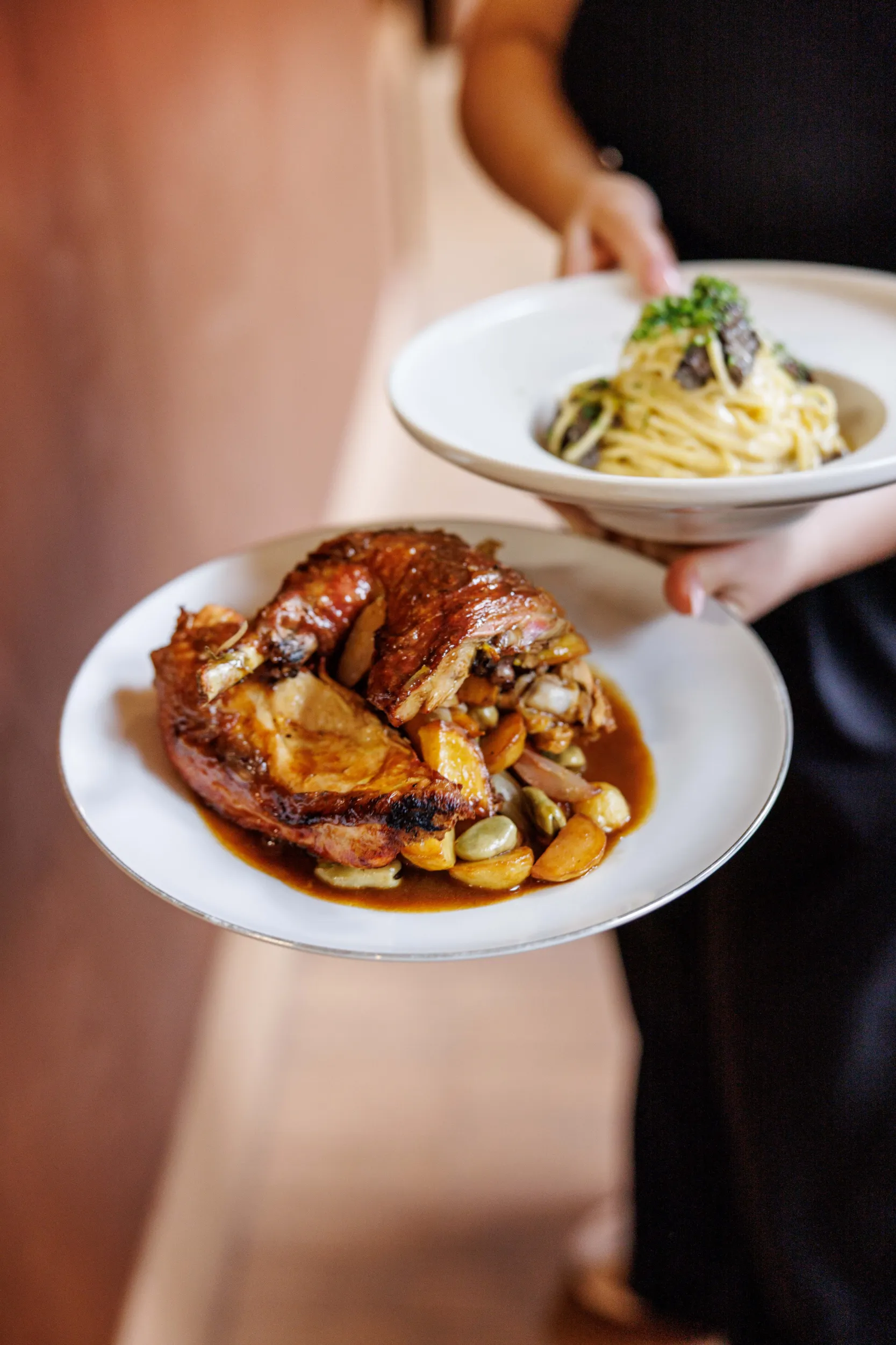Server holding plates of truffle spaghetti and roast meat - Santopalato, Rome, Italy
