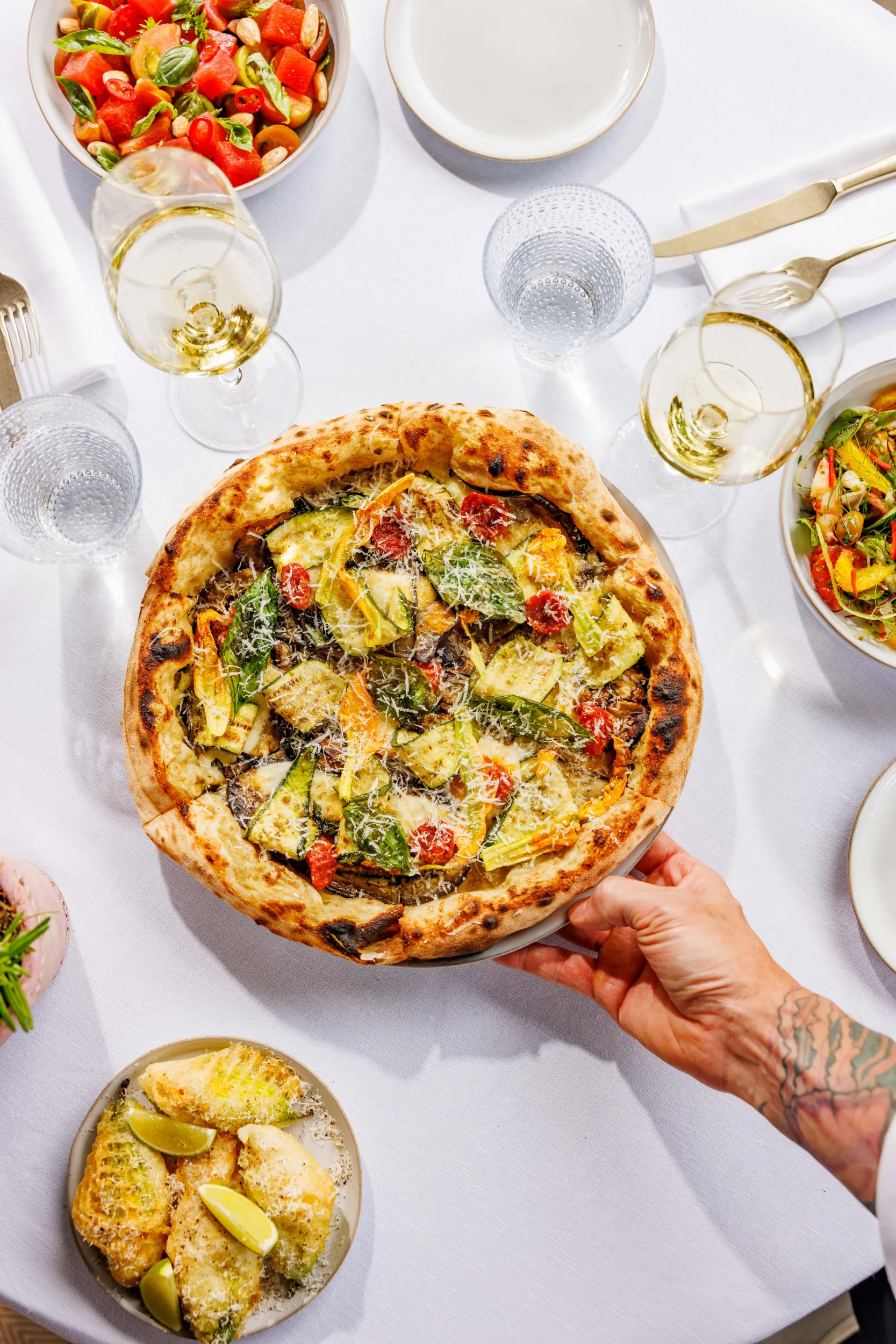 Green pizza being served at a table with wine and salad - Collegio alla Querce, Florence, Italy