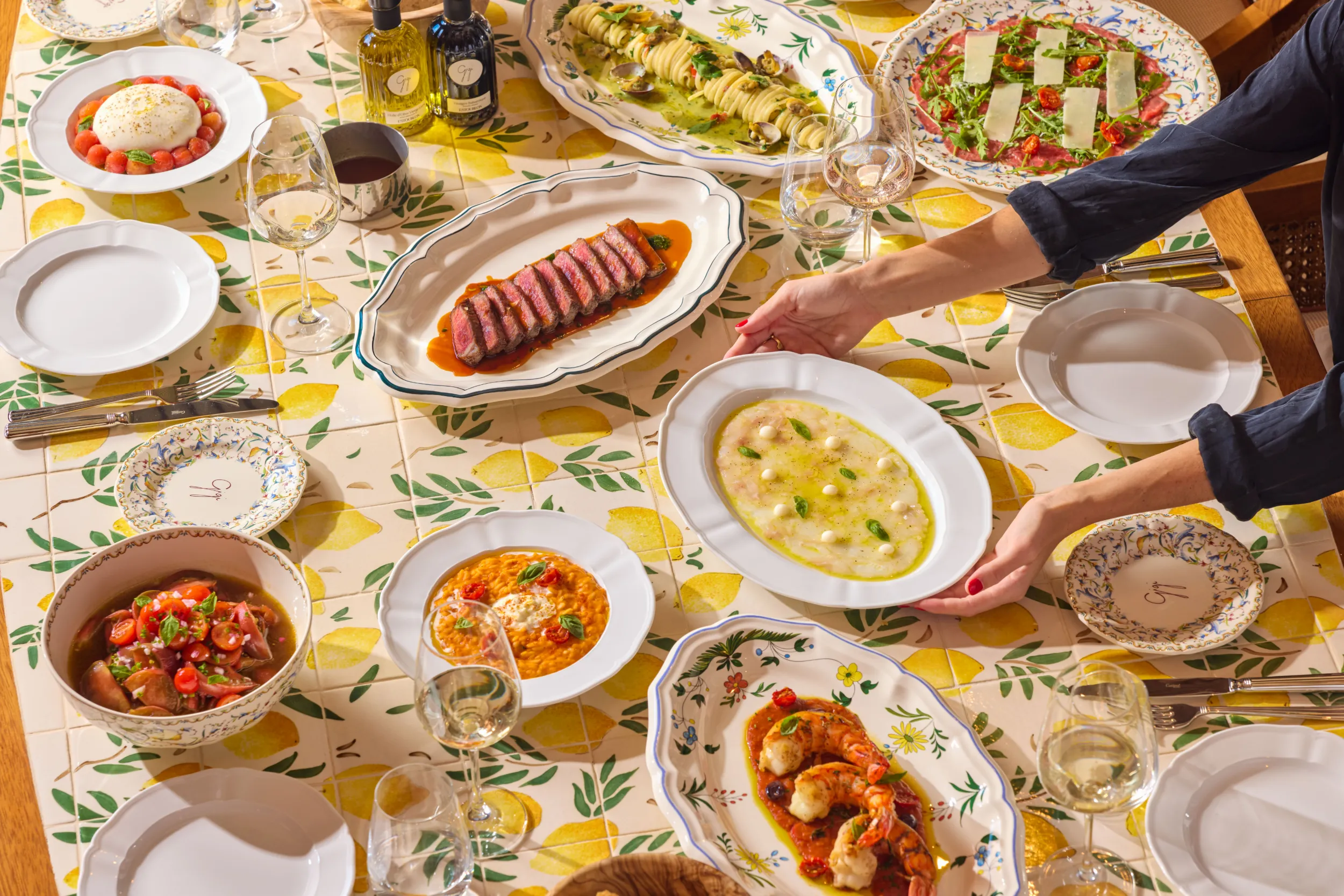 Table laden with shared dishes on a lemon-print cloth - Gigi Rigolatto, Delano Miami, US