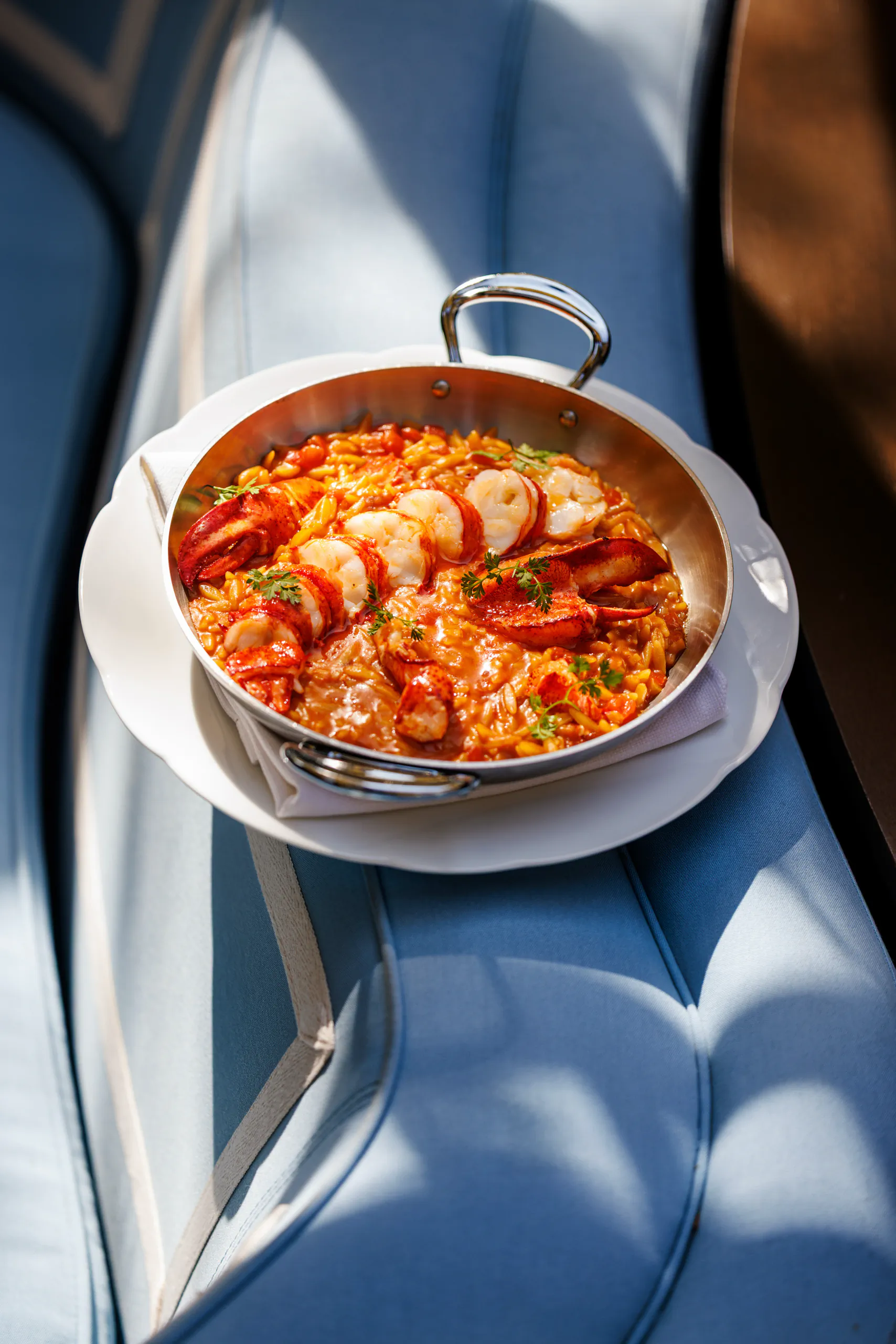 Lobster risotto in a copper pan on a blue banquette - The Wilde, Milan, Italy