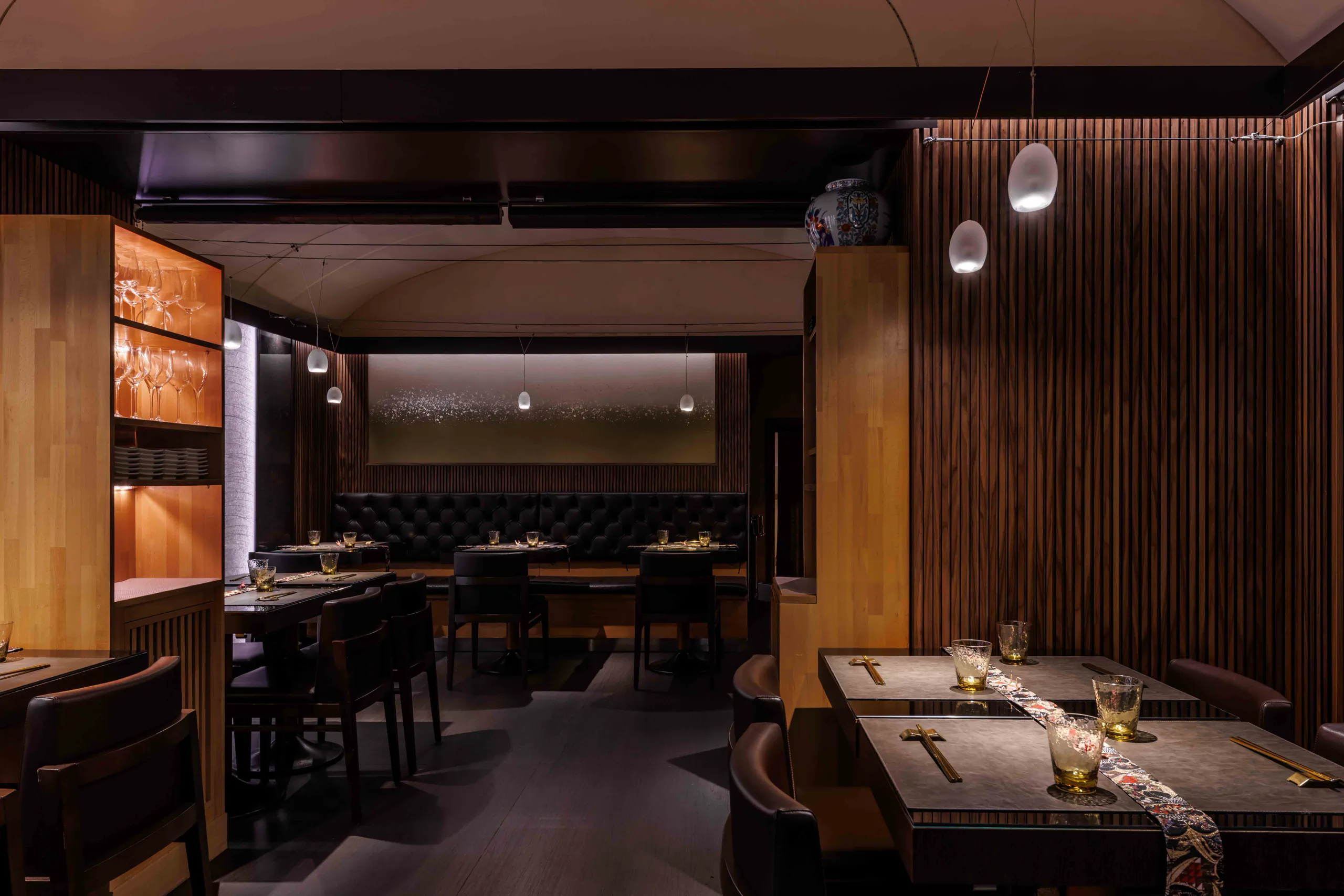 Elegant dark-wood restaurant with set tables and banquette seating