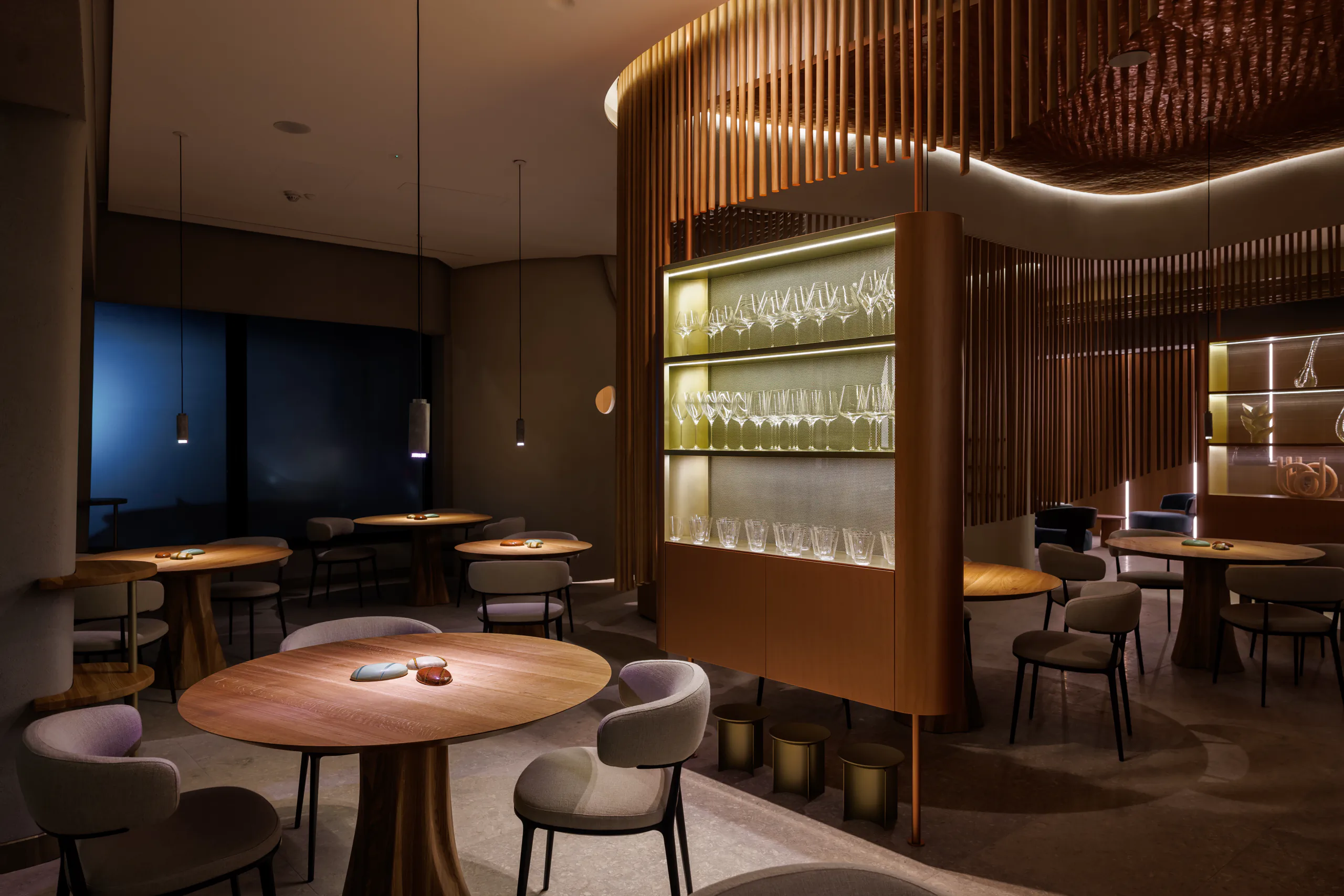 Elegant restaurant interior with a backlit shelf of glassware and wine