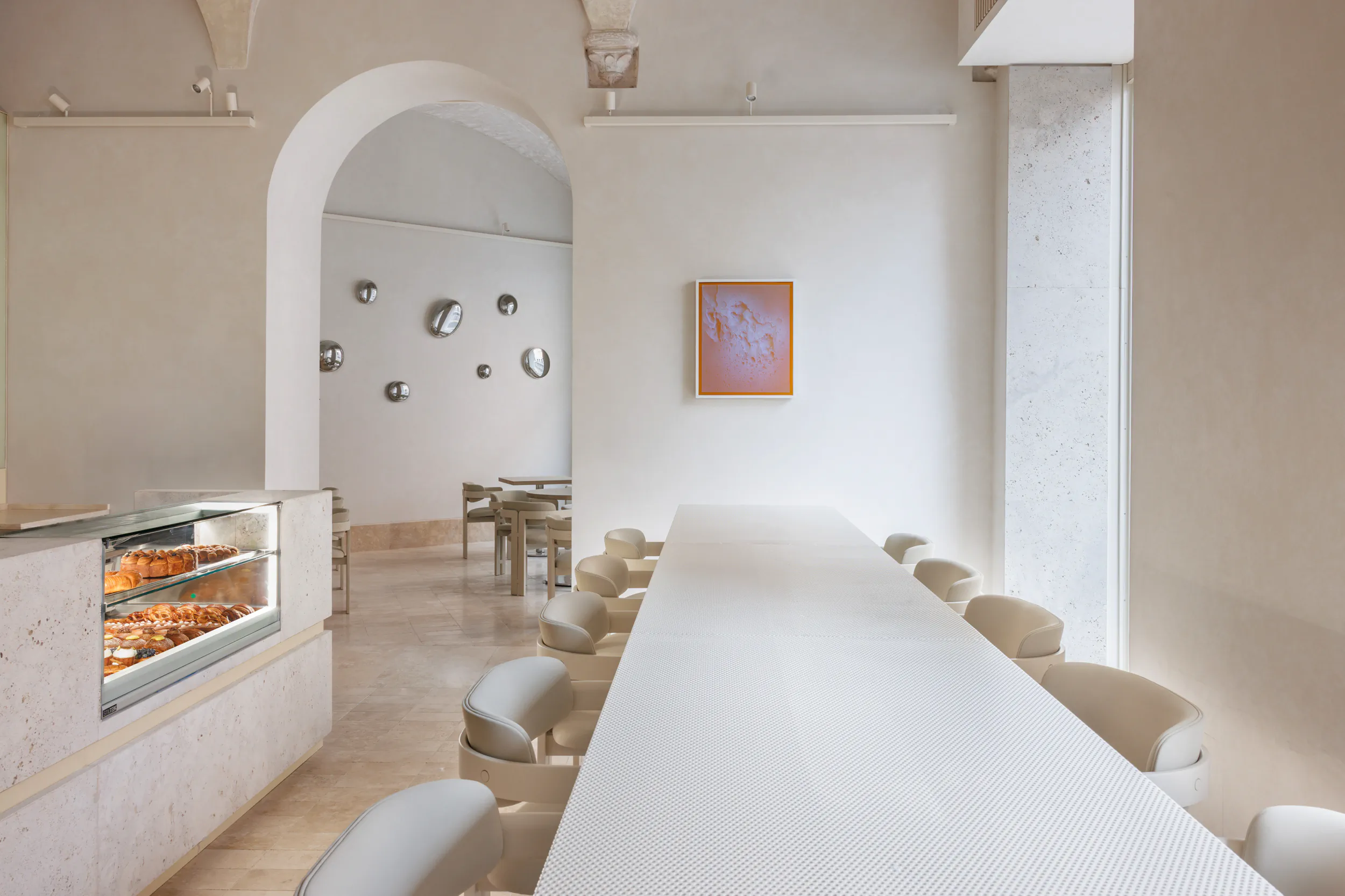 Bright minimalist dining room with a long communal table and a fireplace