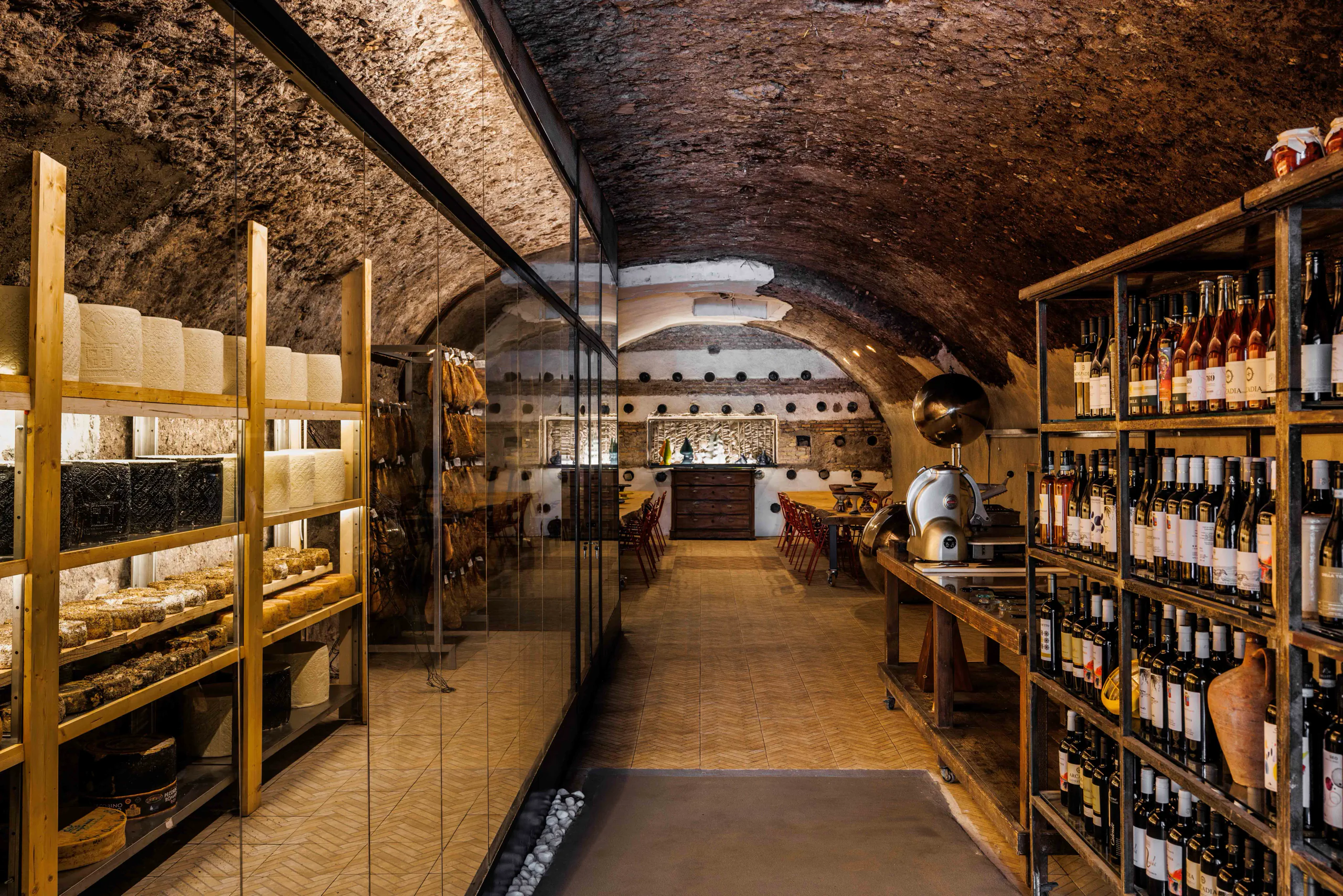 Vaulted wine cellar with rows of bottles and a dining area at the far end