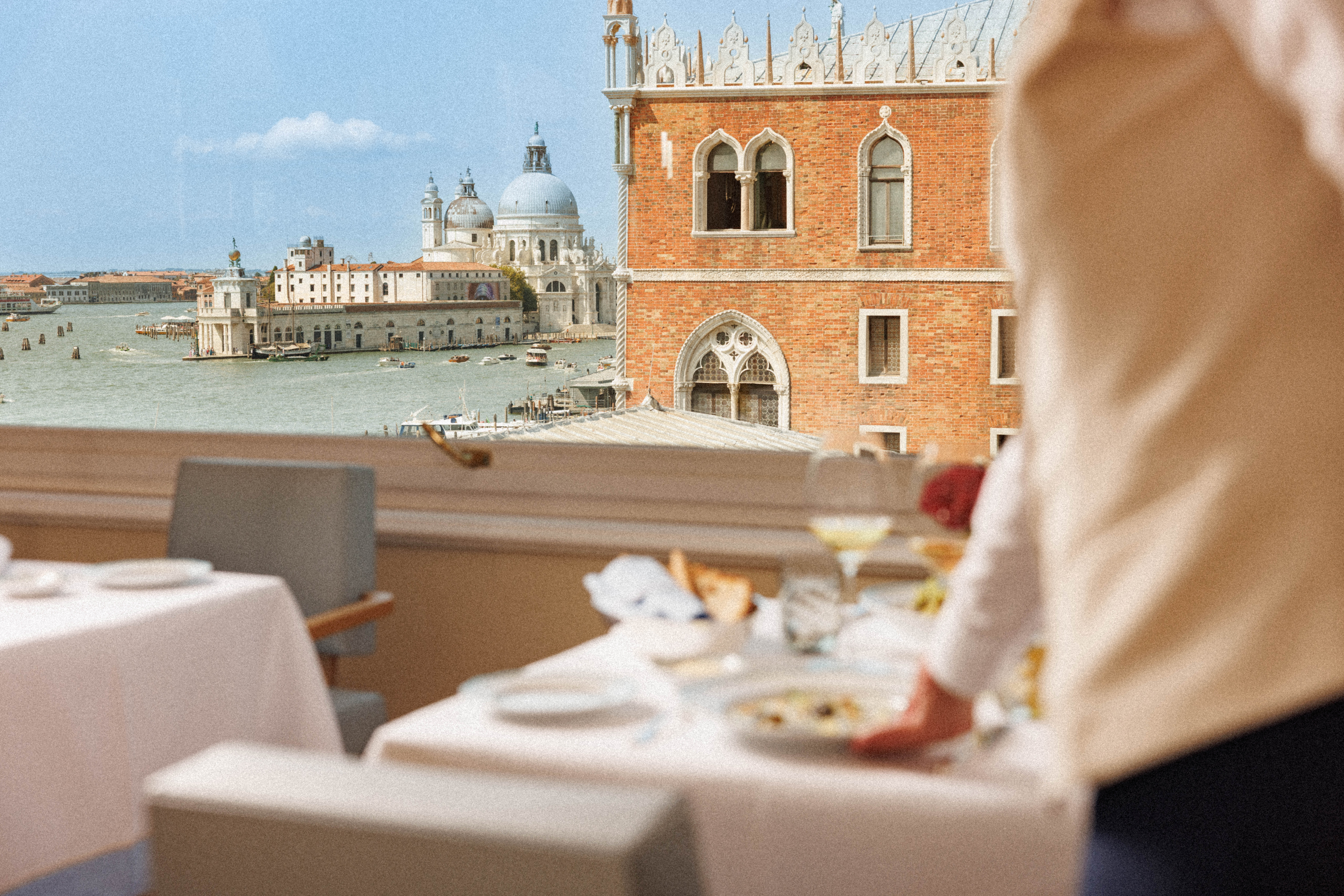 Terrace restaurant table overlooking the Venice lagoon with a waiter serving — Hotel Danieli, Venice